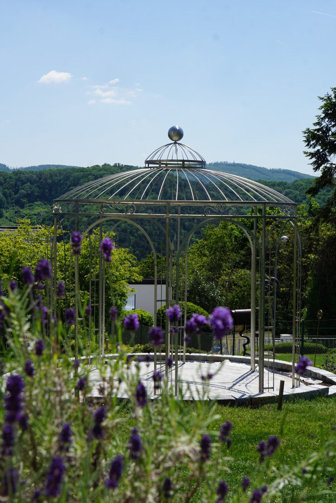 Seitliche Ansicht des Edelstahlpavillons mit Blumen im Vordergrund